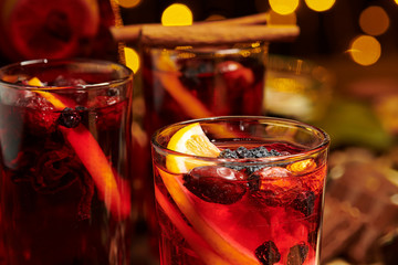 Christmas mulled wine or gluhwein with spices, chocolate sweets and orange slices on rustic table, traditional drink on winter holiday, christmas lights and decorations