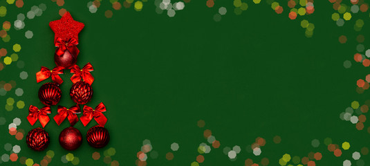 Greeting card banner for Christmas and New Year on a green background with a minimalistic Christmas tree made of red Christmas balls and red bows with a bokeh frame. Chinese New Year.