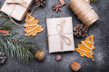 Christmas presents, gingerbreads, pine twigs and cones covered with snow on dark background