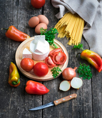 food ingredients - pasta, vegetables, cheese, eggs on a wooden background