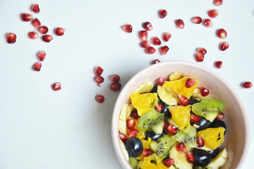 salad with fresh fruits and berries made from orange grapes and pomegranate and kiwi on a black background diet healthy nutrition vegetarianism