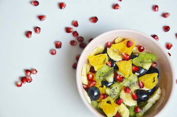 salad with fresh fruits and berries made from orange grapes and pomegranate and kiwi on a black background diet healthy nutrition vegetarianism