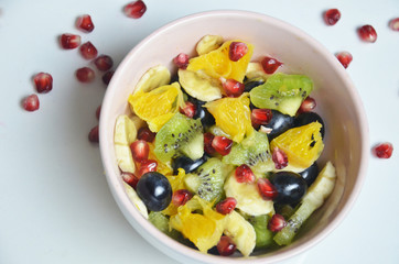 salad with fresh fruits and berries made from orange grapes and pomegranate and kiwi on a black background diet healthy nutrition vegetarianism