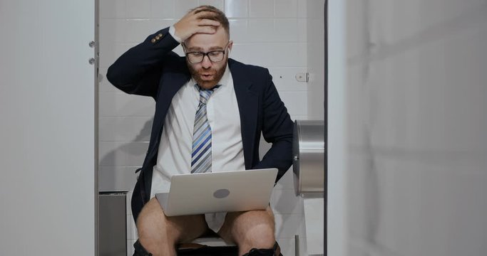 Businessman with notebook sitting in toilet.