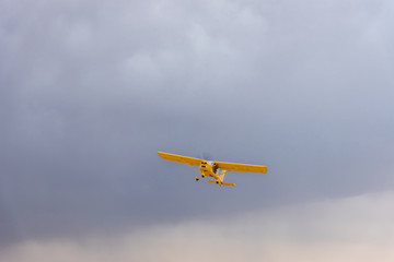 Light yellow turboprop aircraft flies across the sky among the clouds
