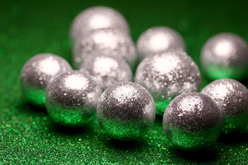 Macro abstract view of glittery silver holiday baubles on a sparkling green background