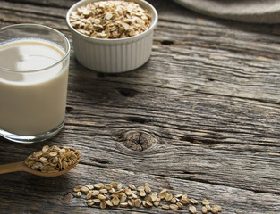 Oat milk in glass  on  wooden background.