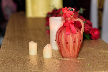 Decorated pitcher. Burning candles on the table. Red roses, wedding tradition.