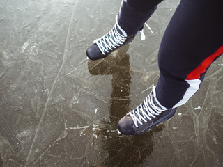Legs of a girl in black hockey skates on ice. Photo above