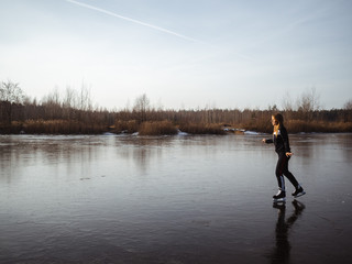 A young girl in a tracksuit skates on a frozen lake