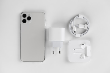 Fototapeta premium Close-up of a smartphone with three cameras, a charger, headphones and a cable.