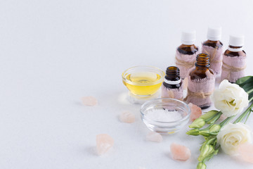 Spa composition with oils, sea salt, candles and a branch of white eustoma on a white background. Skin care concept