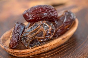 Juicy dates in a bowl on a old wooden table .