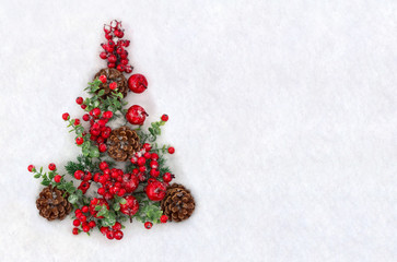 Christmas decoration. Cones pine, twigs christmas tree, red berries and red apples on snow with space for text. Top view, flat lay