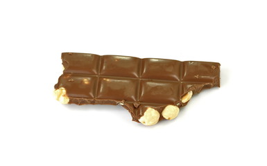 A broken piece of chocolate with hazelnuts isolated on white background. Milk chocolate tiles with nuts isolated on white.