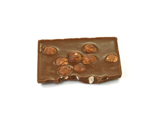 A broken piece of chocolate with hazelnuts isolated on white background. Milk chocolate tiles with nuts isolated on white.