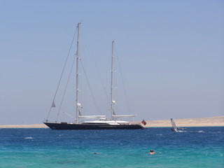 Fototapeta na wymiar Seascape. Sailing ship in the blue sea on a background of blue sky and islands.