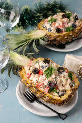Festive salad with chicken in halves of pineapple on a light blue background, New Year, Valentine's Day, Romantic dinner, vertical orientation