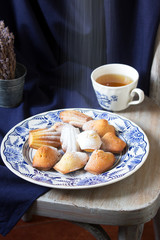 Lavender madeleines on a porcelain plate on a blue background. Rustic style.