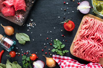 Raw beef fillet ready for grilling. Veal fillet and minced meat on a wooden cutting board with cherry tomatoes, hot pepper and herbs. Ingredients for soup or borsch. copy space. top view.