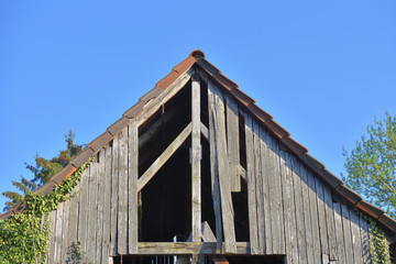 Fototapeta na wymiar Old wooden and holey shed roof against a blue sky in a European village