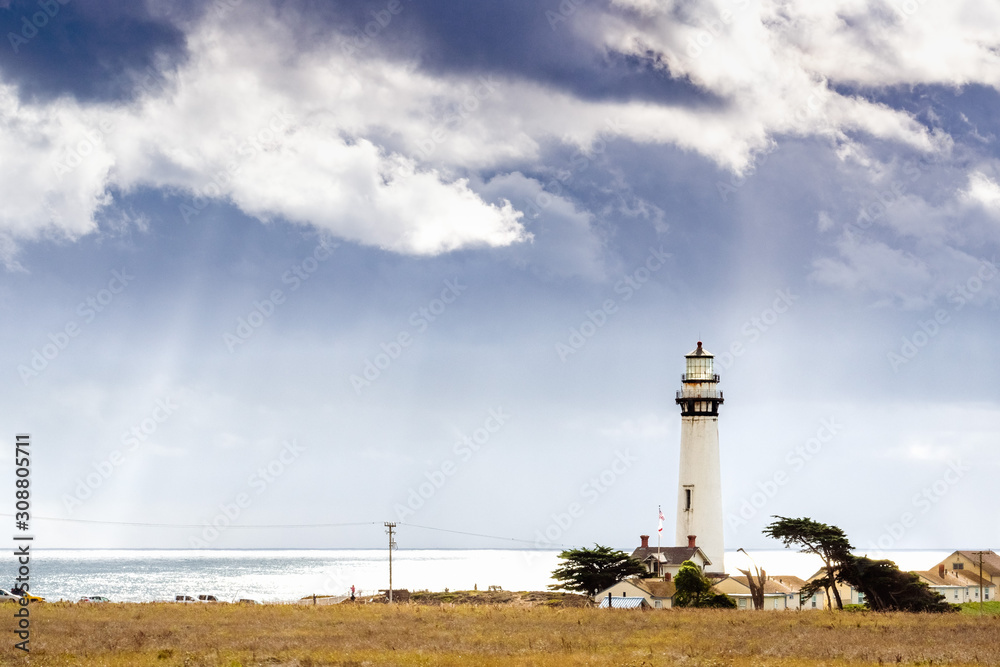 Wall mural Pigeon Point Lighthouse on the Pacific Ocean coastline; sun rays bursting through storm clouds; Pescadero, San Francisco bay area, California