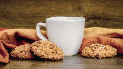 White cup with tea and cookies on wooden table_