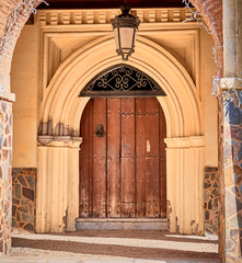 Entrance door to a historic building, with wooden gate, sculpted solid iron knocker and gothic arch