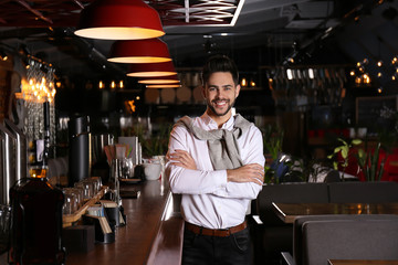 Young business owner standing near counter in his cafe