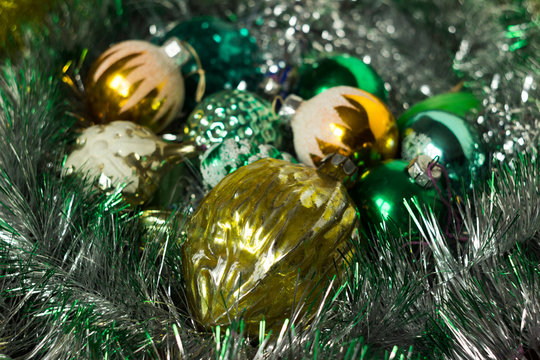 New Year's yellow and green toys lie on a shiny garland. Old toys in the form of a nut, with the image of snowflakes, balls. New year and Christmas background, concept