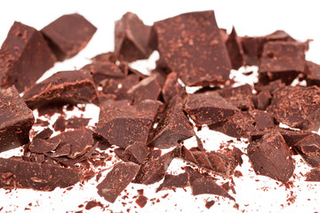 Chopped chocolate pieces on white background. Selective focus.