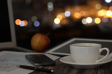 overtime in the evening, work from home, a cup of coffee and a laptop on a night background with...