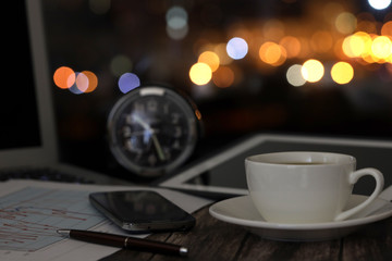 overtime in the evening, work from home, a cup of coffee and a laptop on a night background with beautiful bokeh