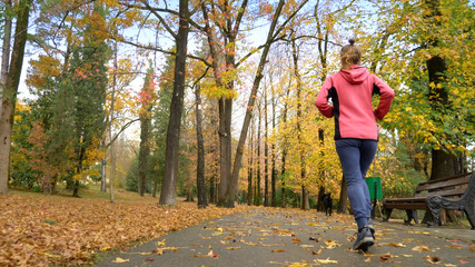 athletic young girl running in autumn Park after rain. rear view