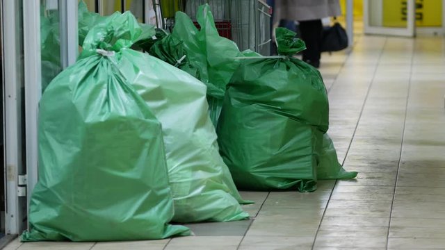 Large green sealed mail bags in the corridor. Plastic fabric polypropylene bags filled with goods or boxes lie on the floor.