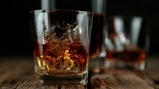 Super slow motion of falling ice cube into whiskey drink. Filmed on high speed cinema camera, 1000 fps.