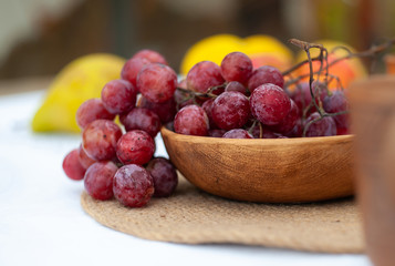 close-up of red grape in rustic ceramic plate on a white tablecloth with blurred unclear background
