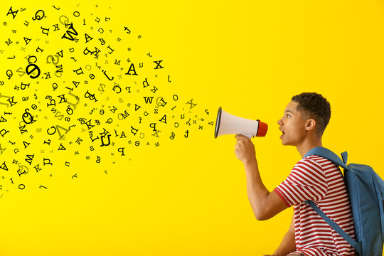 Portrait of African-American teenage boy with megaphone on color background