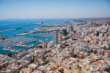 Fototapeta premium Beautiful wide aerial view of Alicante, Valencian Community, Spain with port of Alicante, beach and marina, with mountains and skyline, seen from Santa Barbara Castle on Mount Benacantil, sunny day