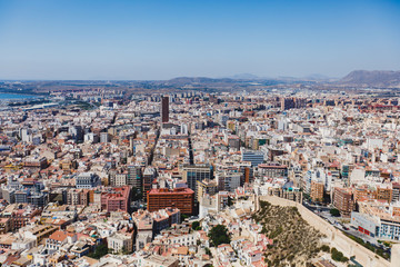 Obraz premium Beautiful wide aerial view of Alicante, Valencian Community, Spain with port of Alicante, beach and marina, with mountains and skyline, seen from Santa Barbara Castle on Mount Benacantil, sunny day