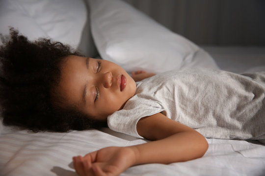 Little African-American girl sleeping in bed at night