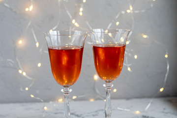 Orange wine is poured into two glasses. Celebratory drink. Family celebration.