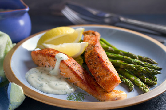 Delicious cooked salmon fish fillets with asparagus and lemon wedges