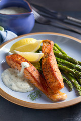 Delicious cooked salmon fish fillets with asparagus and lemon wedges