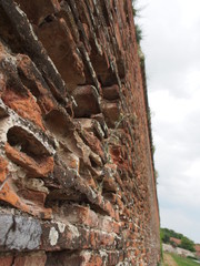 Some brinks are missing in this wall with a background of clouds