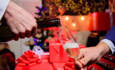 Celebrate new year with champagne. Hands pouring champagne into elegant glass christmas decorations background. Cheers concept. Last minute before new year. Drink champagne or sparkling wine