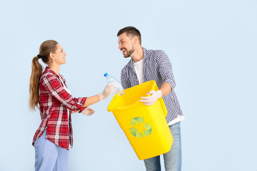 Couple with container for garbage on color background. Concept of recycling