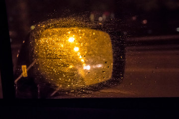 Evening lights and water drops on the car window