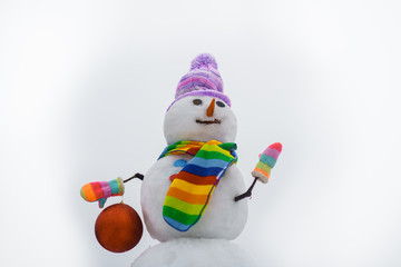 Smiling snowwoman with Christmas toy. Merry Christmas and Happy new year. Snowman hold new year ball. Snow man in winter hat. Christmas background with snowman. Funny snowman in stylish hat and scarf.