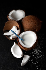 natural fresh coconut milkshake on a dark black background, milk in a plate of coconut